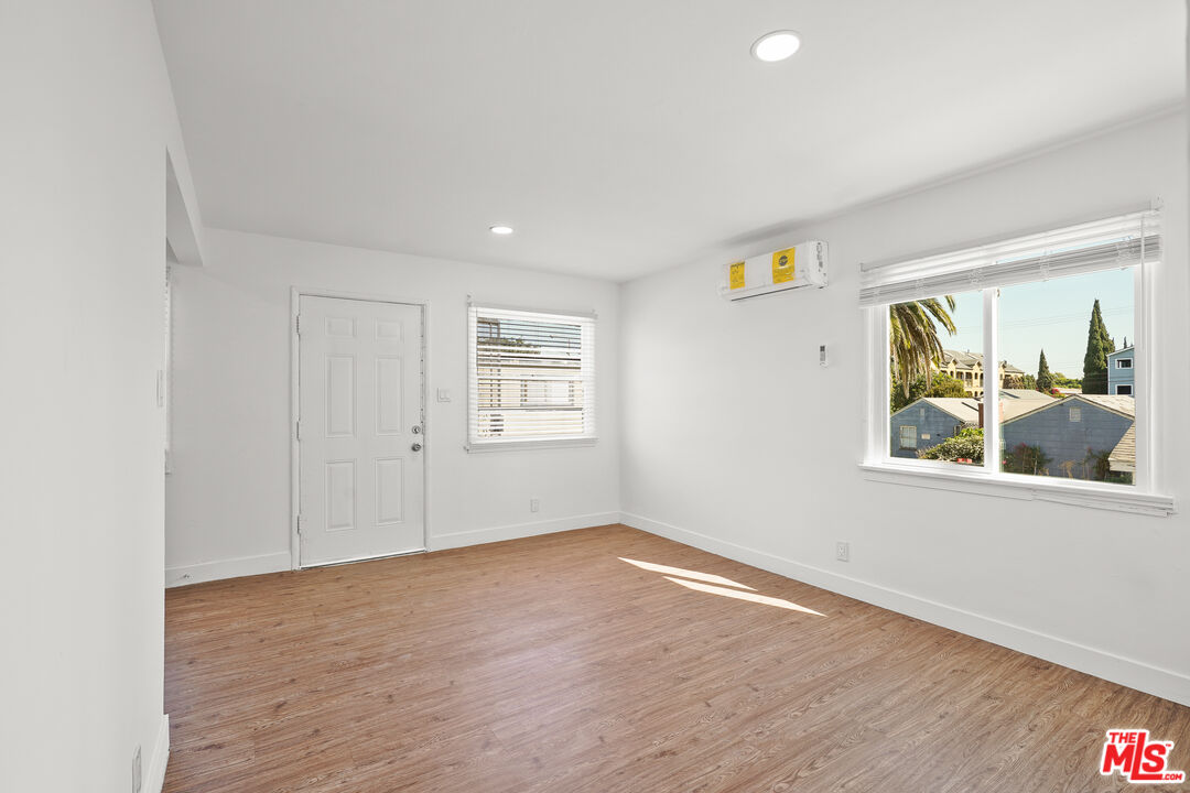 a view of a bedroom with wooden floor and window