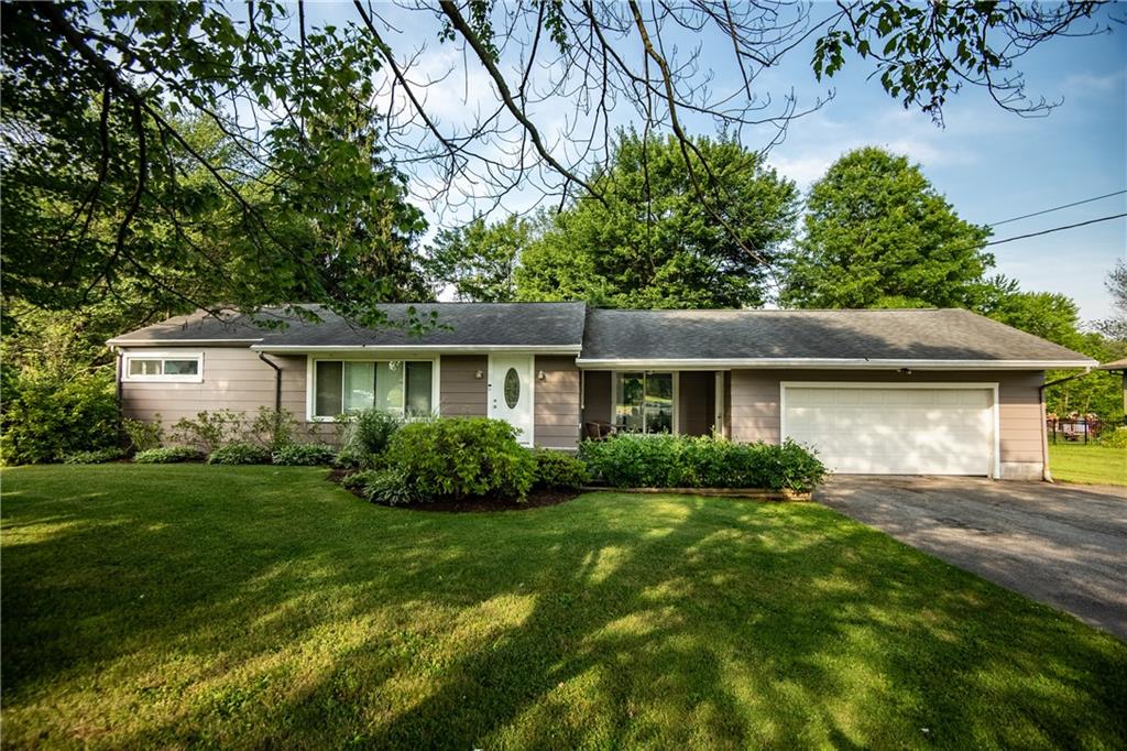 a front view of a house with a yard and green space