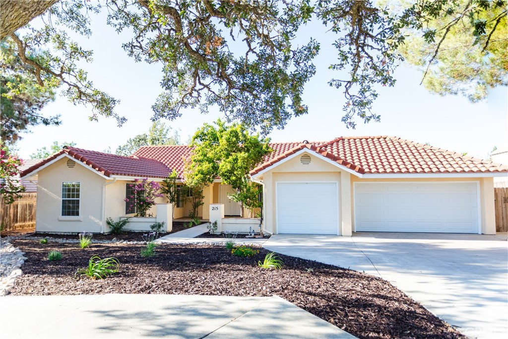 a front view of a house with a garden and trees