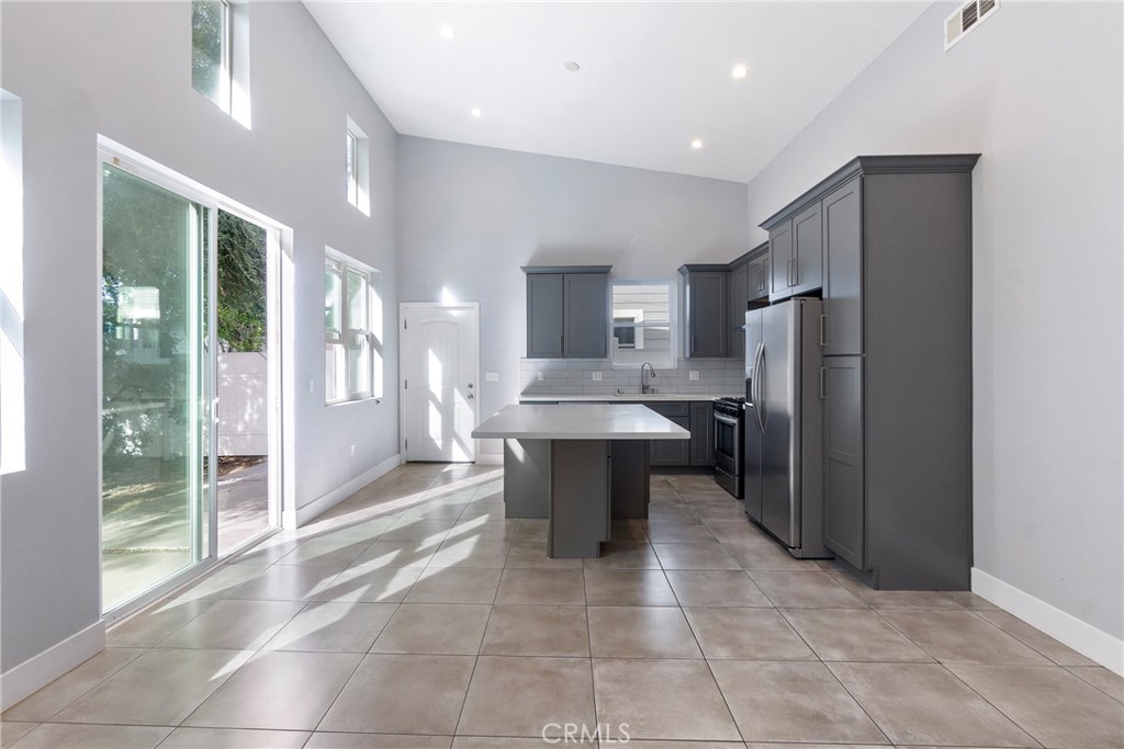 a large kitchen with a large counter top a sink stainless steel appliances and cabinets