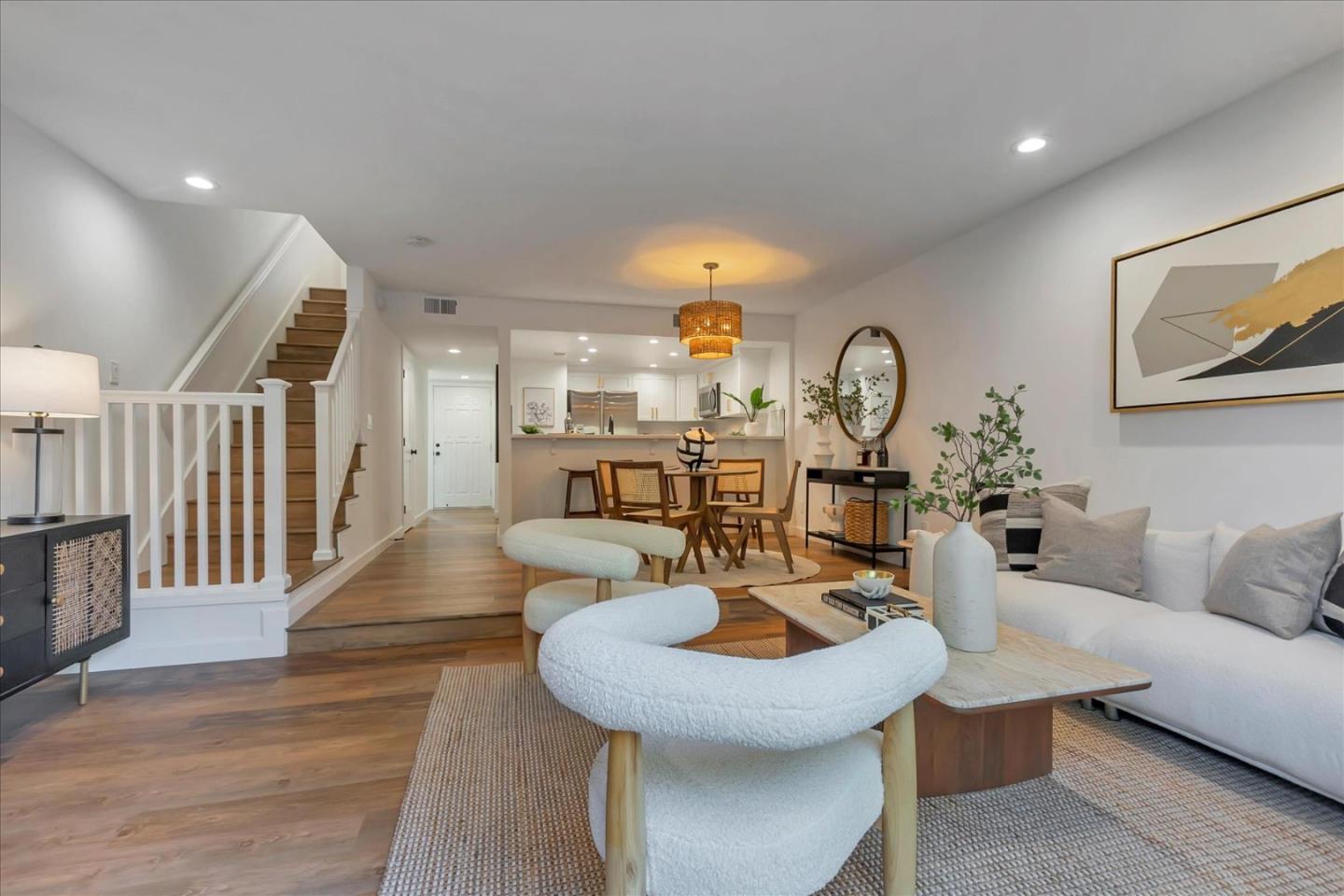 a living room with couches a dining table and chairs with wooden floor