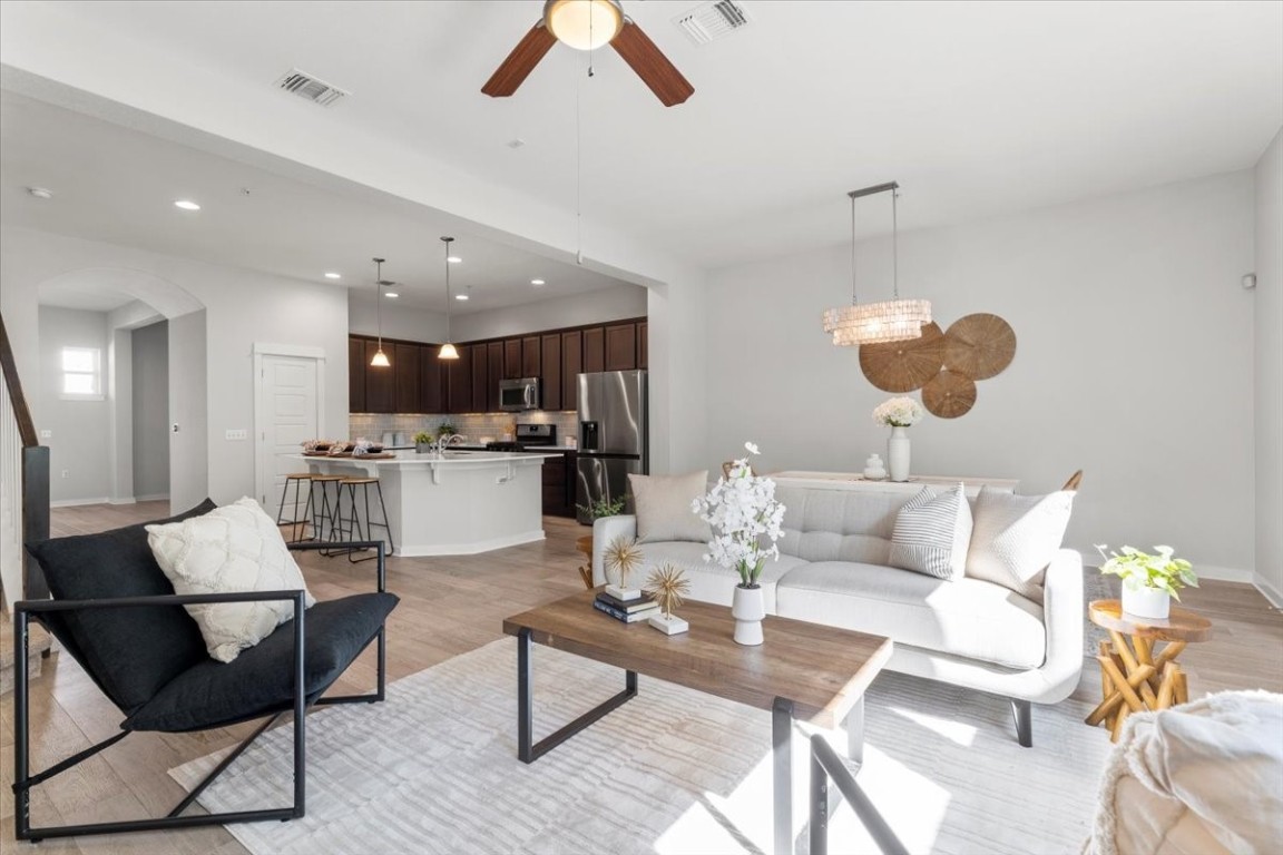 a living room with furniture kitchen view and a chandelier