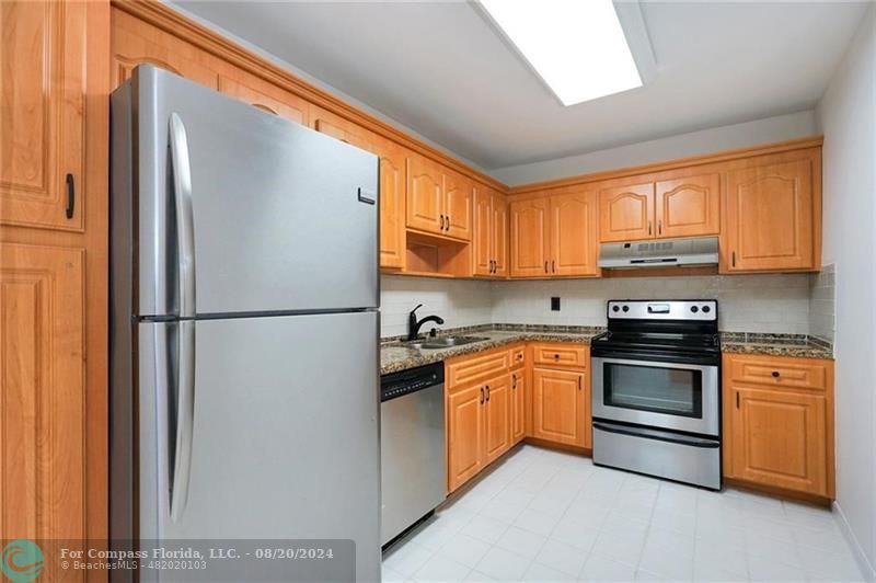 a kitchen with stainless steel appliances granite countertop a refrigerator and a stove top oven