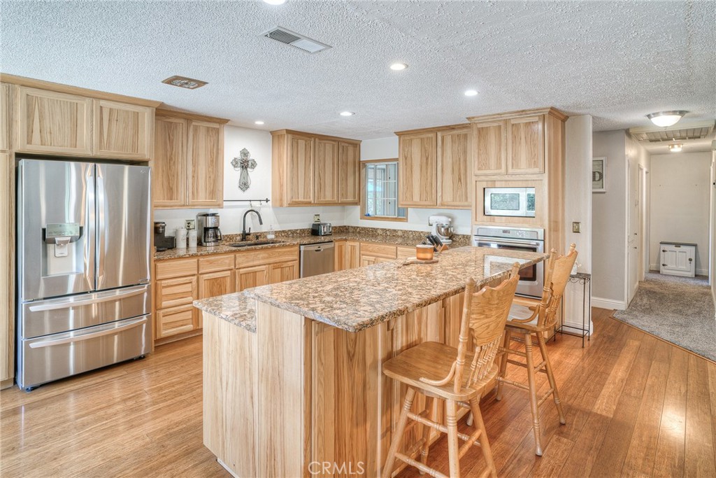 a kitchen with stainless steel appliances granite countertop a refrigerator a stove and a wooden floors