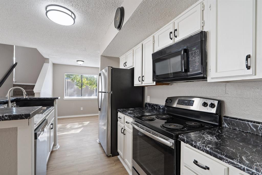 a kitchen with stainless steel appliances granite countertop a stove a sink and a microwave