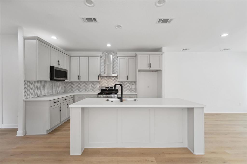 a kitchen with stainless steel appliances granite countertop a sink a stove a refrigerator and white cabinets