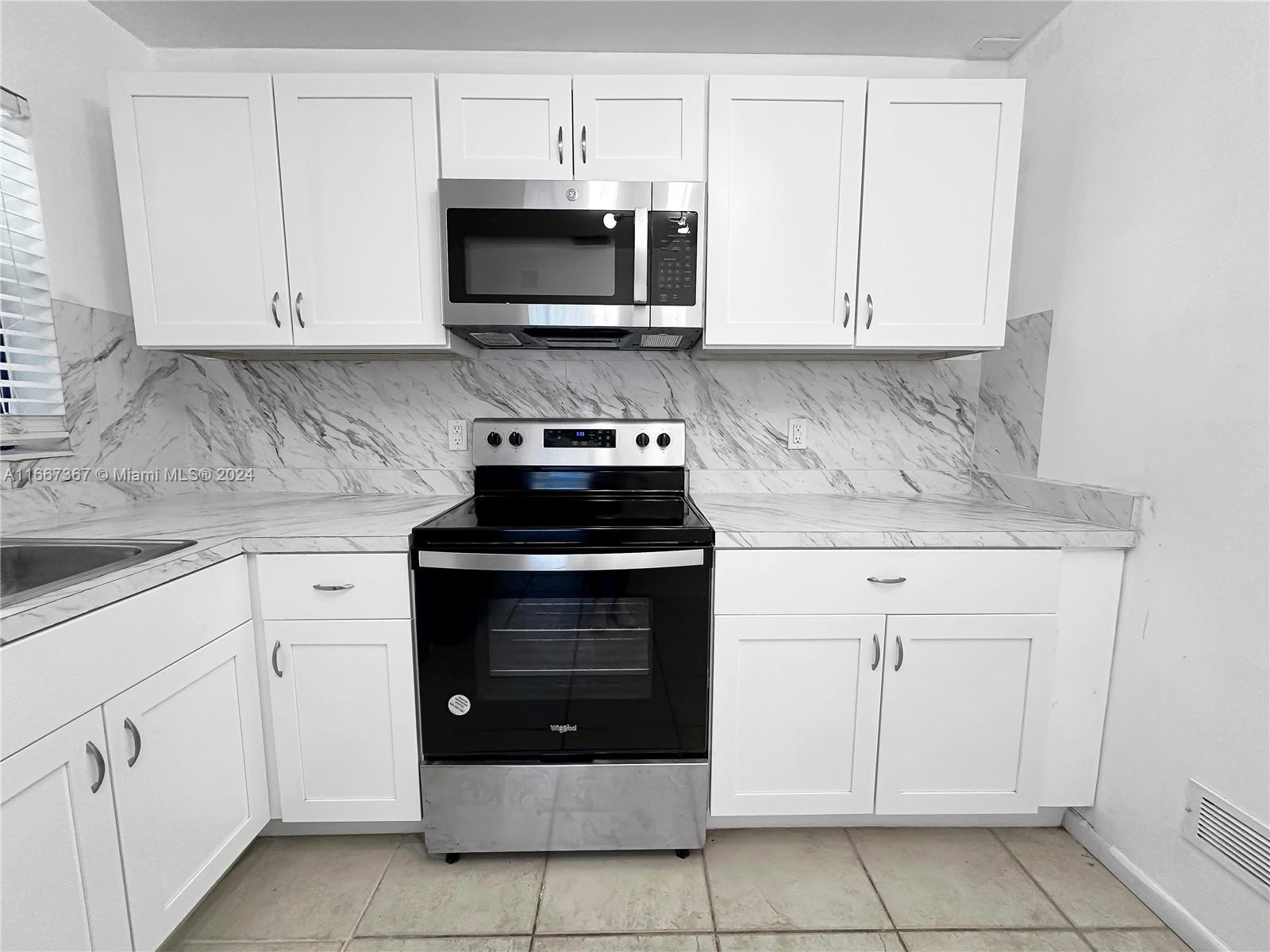 a kitchen with white cabinets and stainless steel appliances