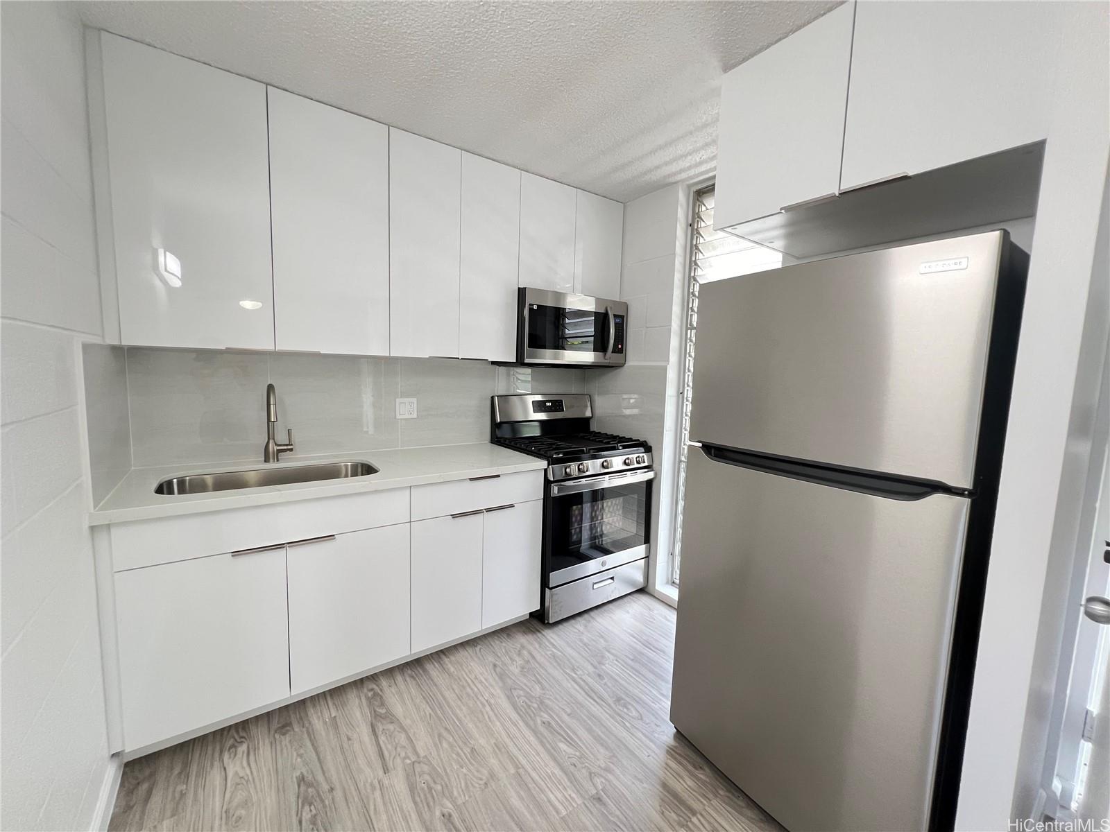 a kitchen with a refrigerator sink and white cabinets