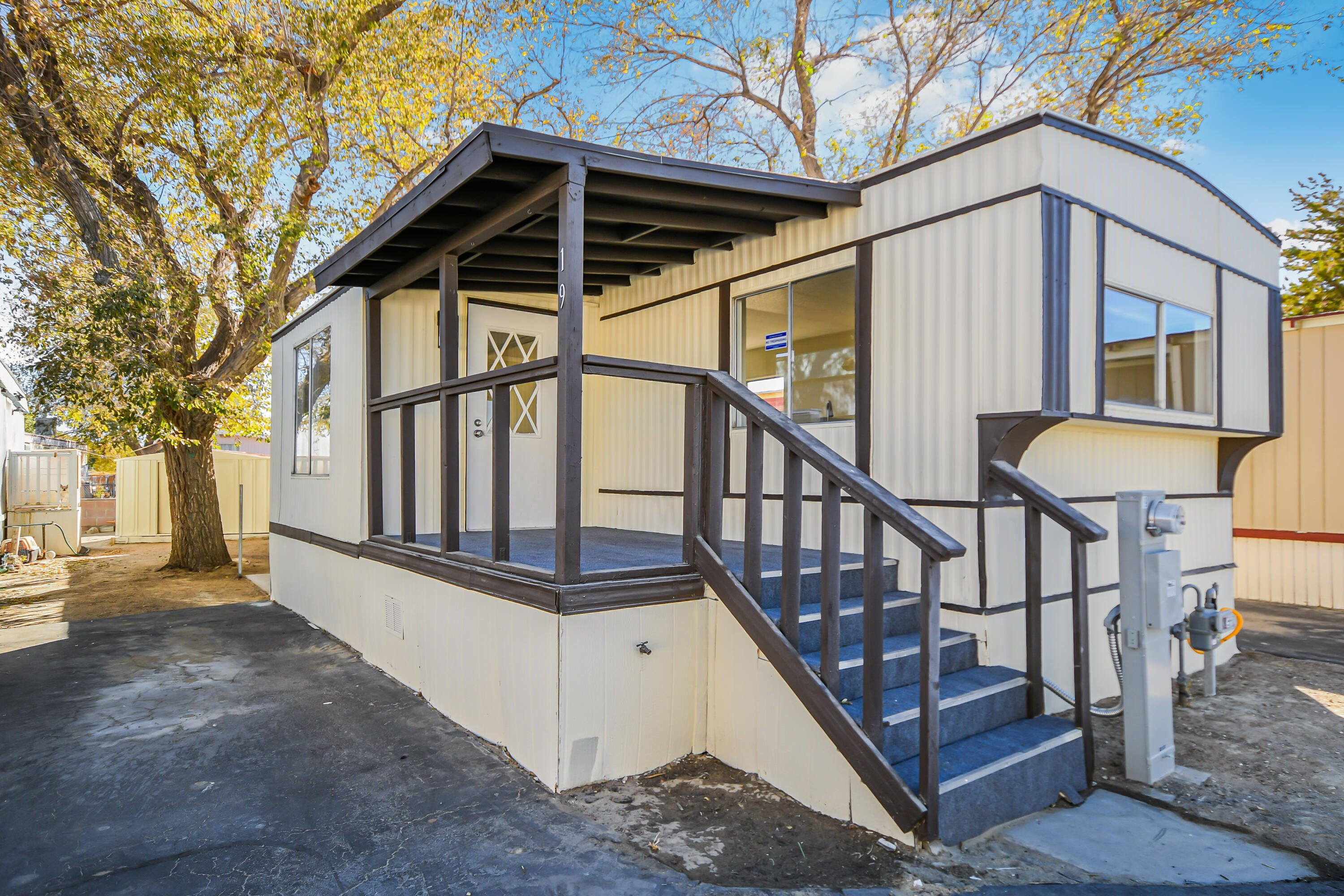 a view of wooden house with a small yard and stairs area