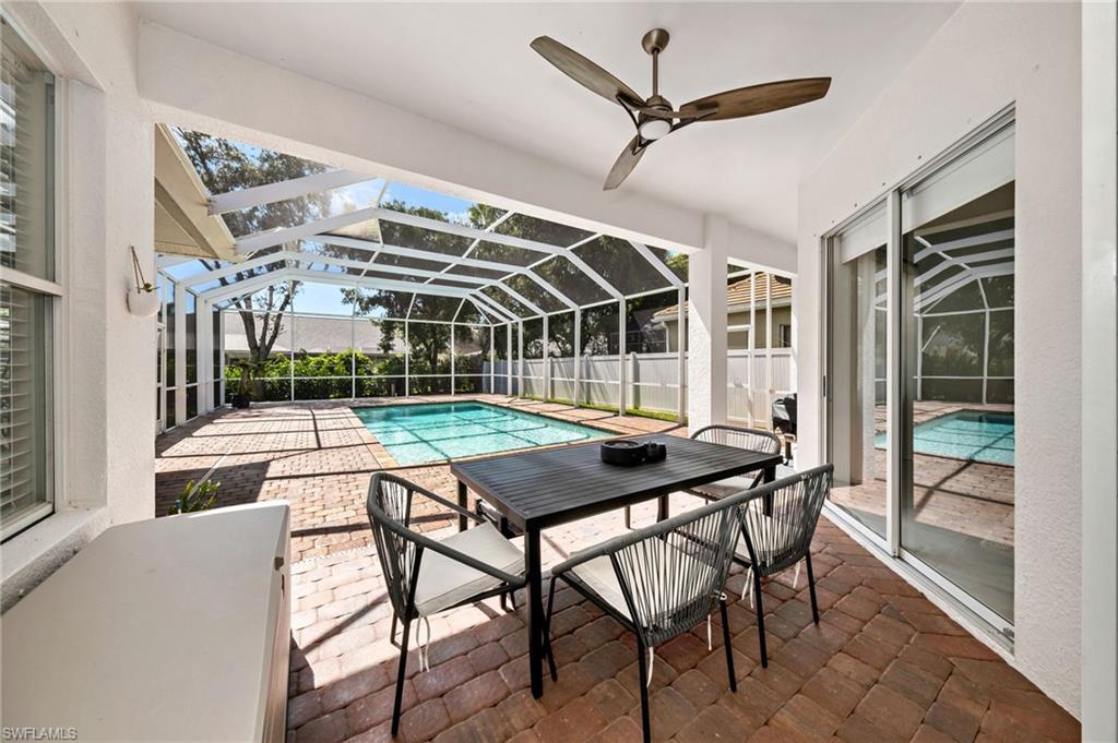 View of swimming pool with glass enclosure, ceiling fan, and a patio