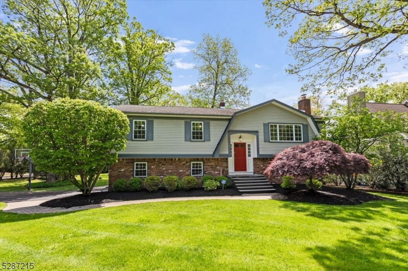 a front view of house with yard and trees in the background