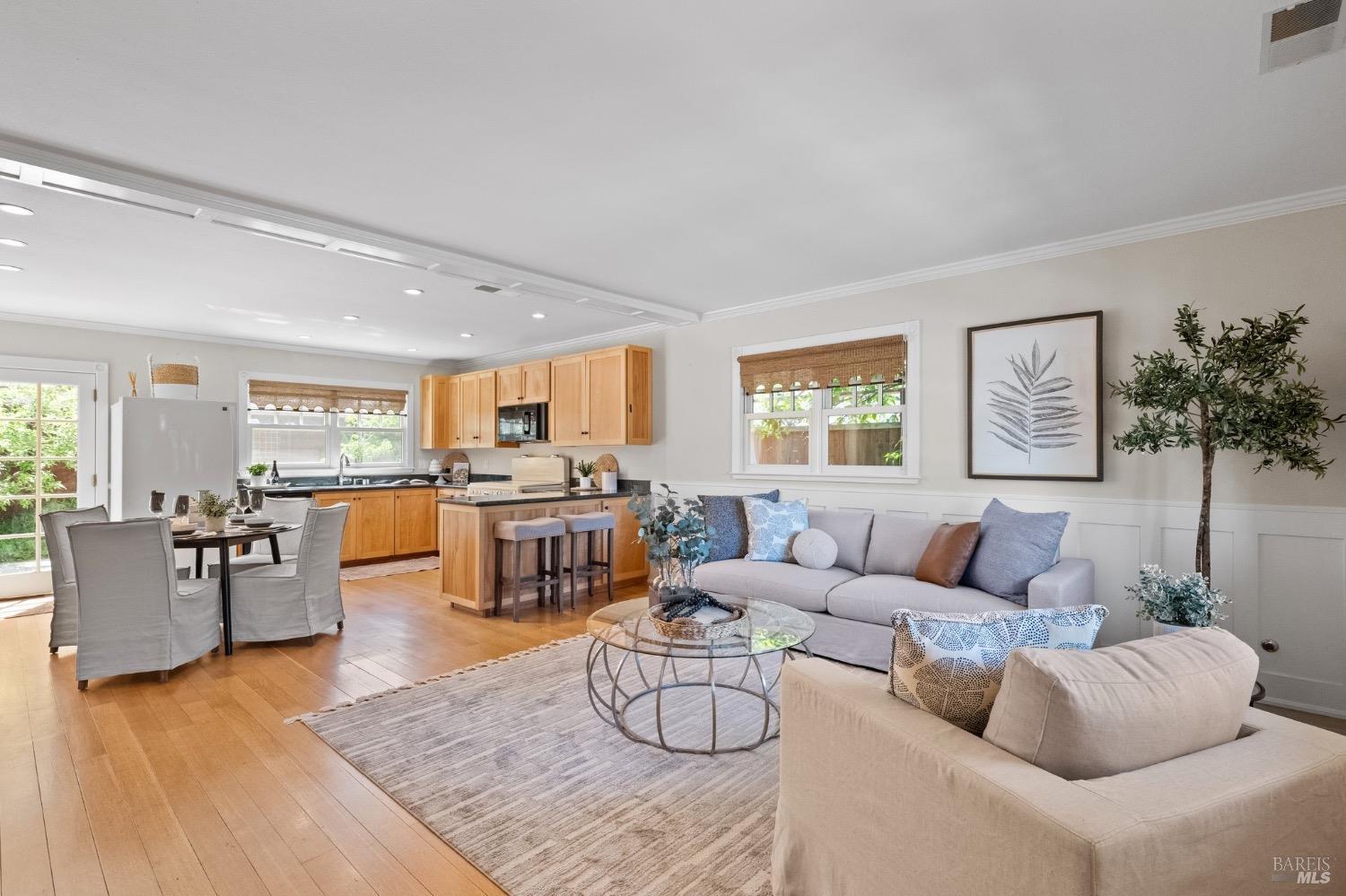 a living room with furniture kitchen view and a large window