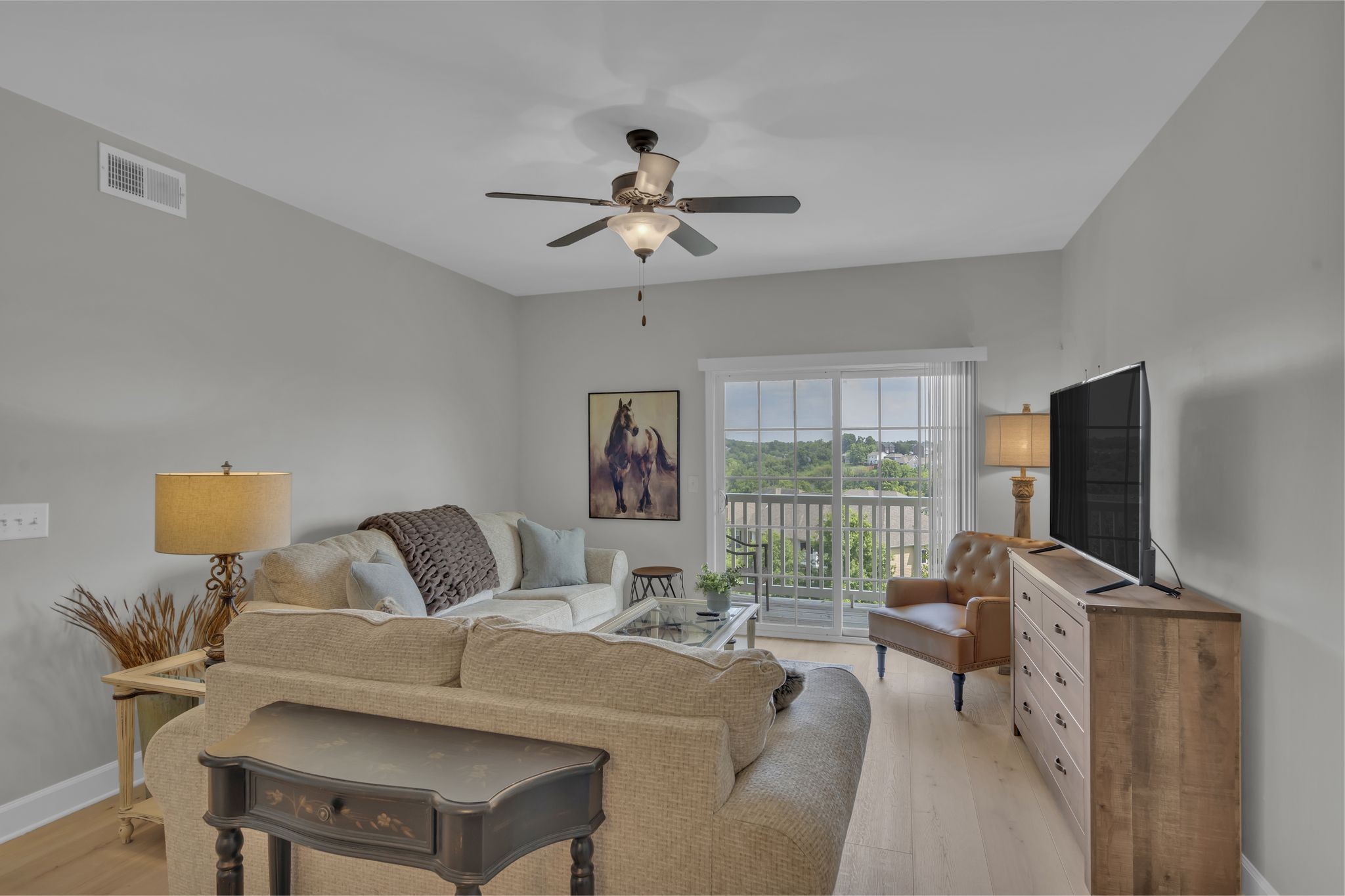 a living room with furniture a ceiling fan and a flat screen tv