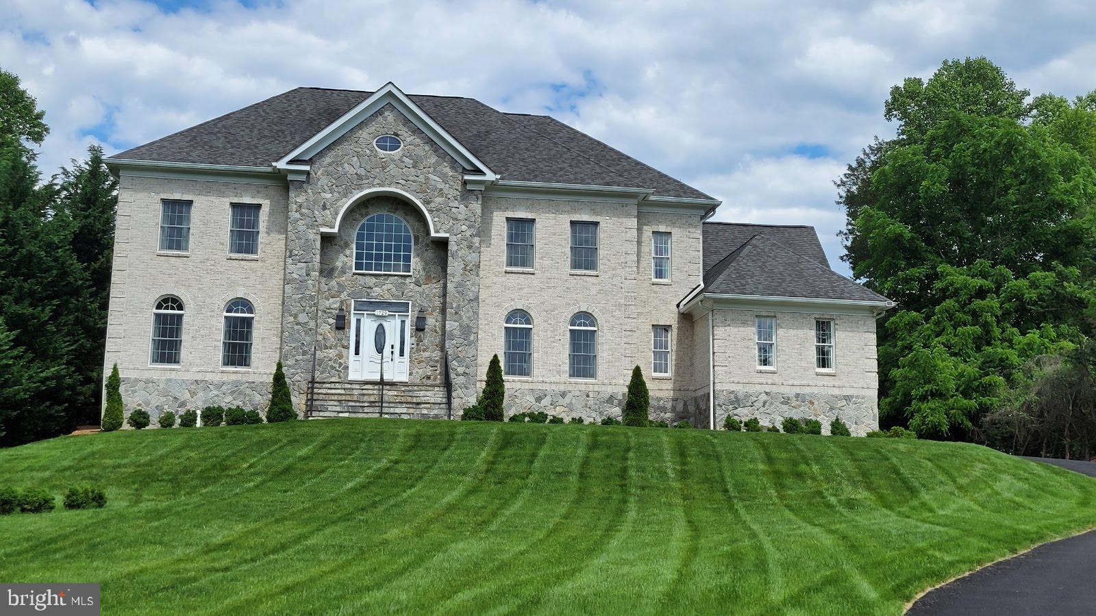 a front view of a house with a yard and trees