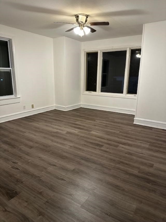 a view of an empty room with wooden floor ceiling fan