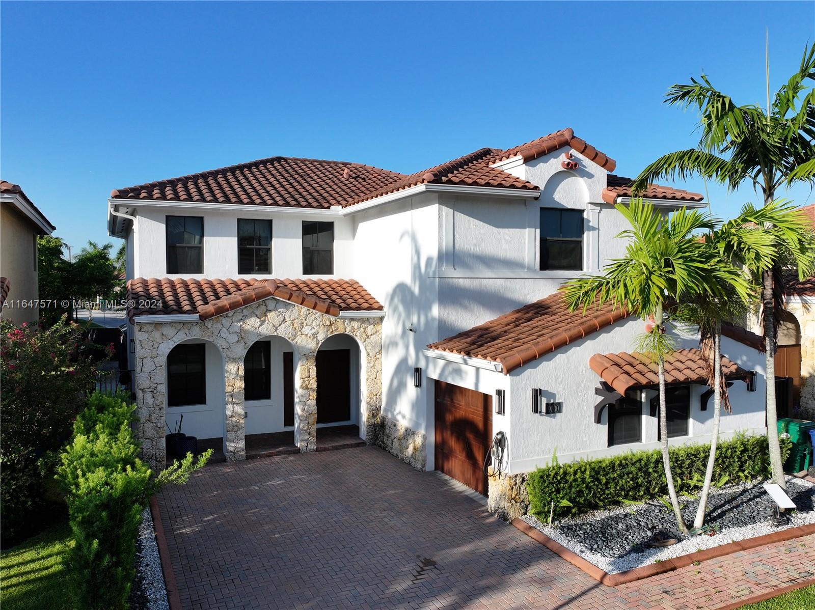 a front view of a house with a yard and potted plants