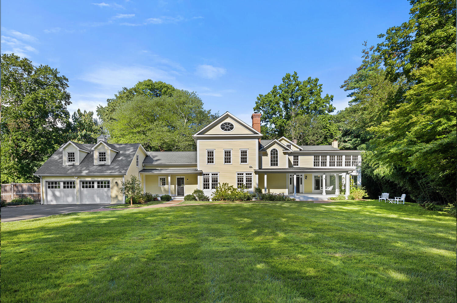 a front view of a house with garden and trees