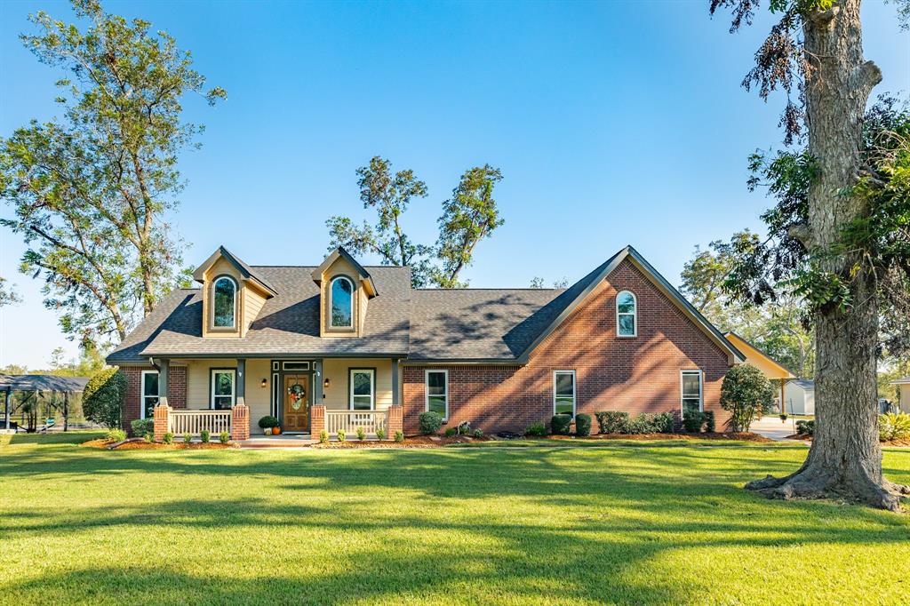 a front view of a house with a big yard and potted plants and large trees