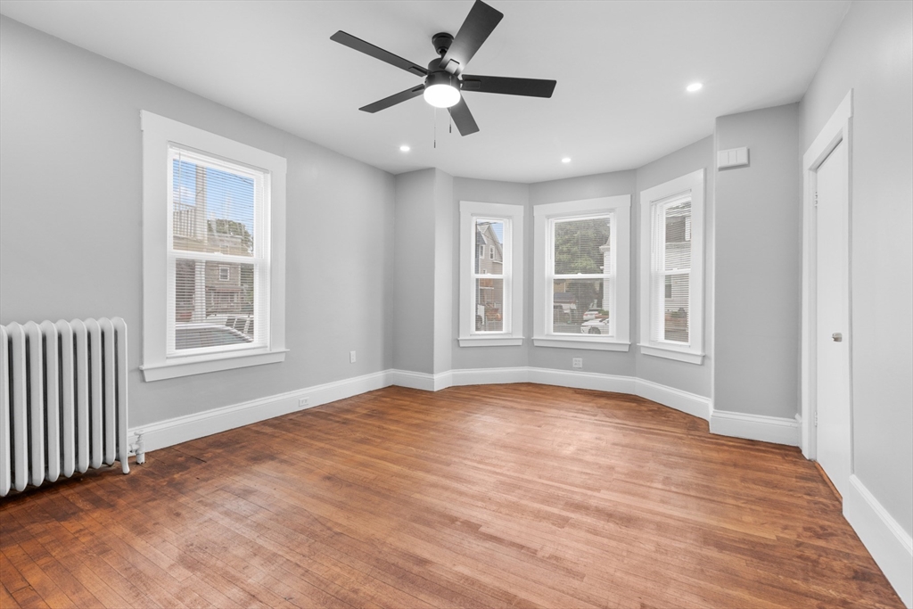 a view of an empty room with a window and wooden floor