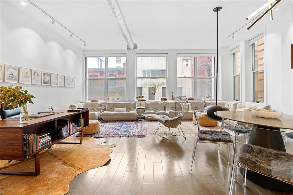 a living room with furniture large window and wooden floor