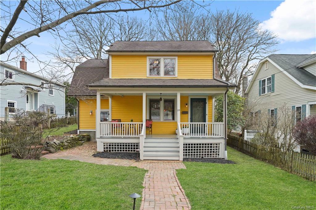 a view of a house with a small yard and a large tree