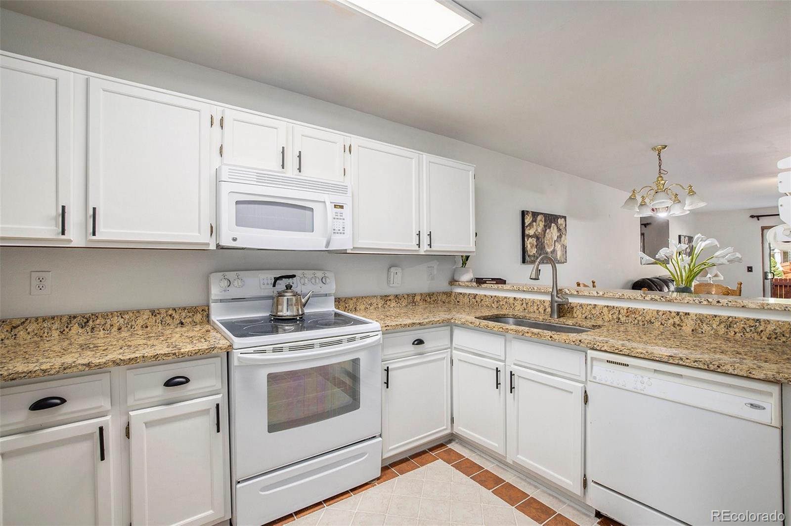 a kitchen with granite countertop white cabinets white appliances and sink