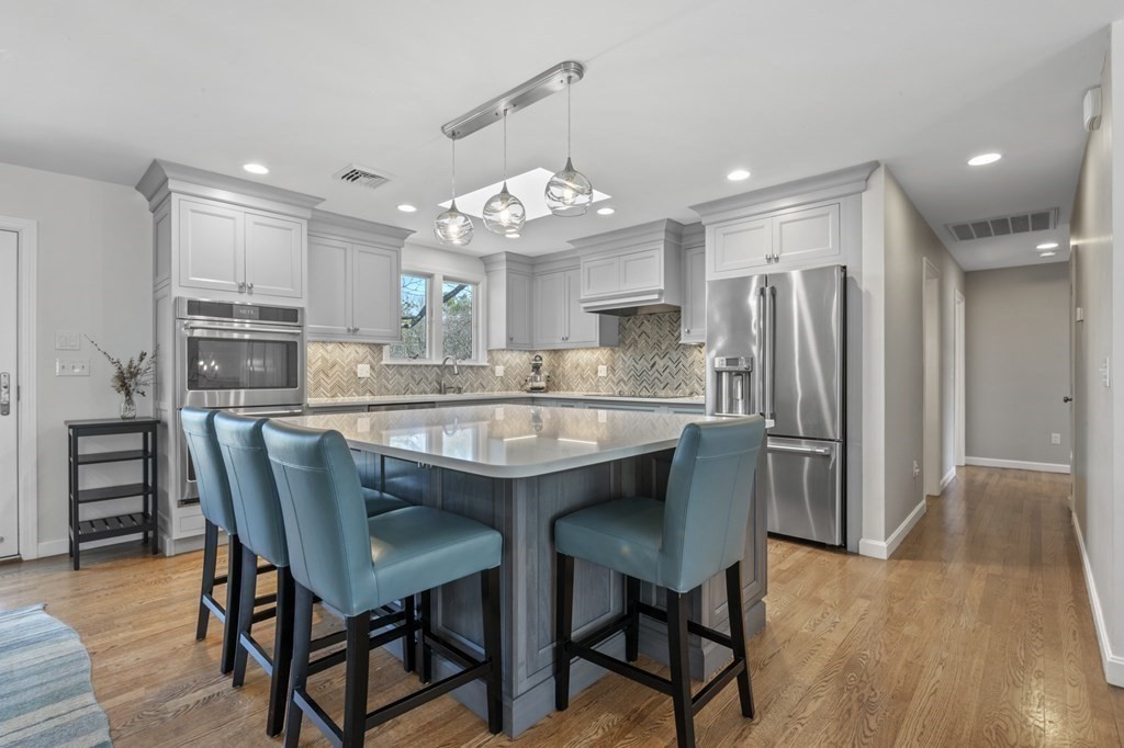 a kitchen with stainless steel appliances granite countertop a dining table chairs refrigerator and cabinets