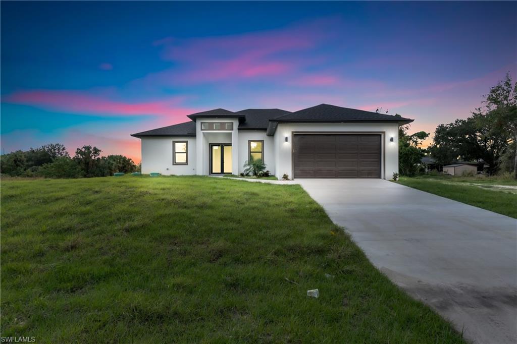 View of front of home with a garage and a yard