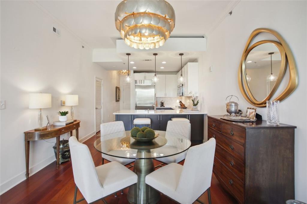 a dining room with wooden floor a chandelier a wooden table and chairs