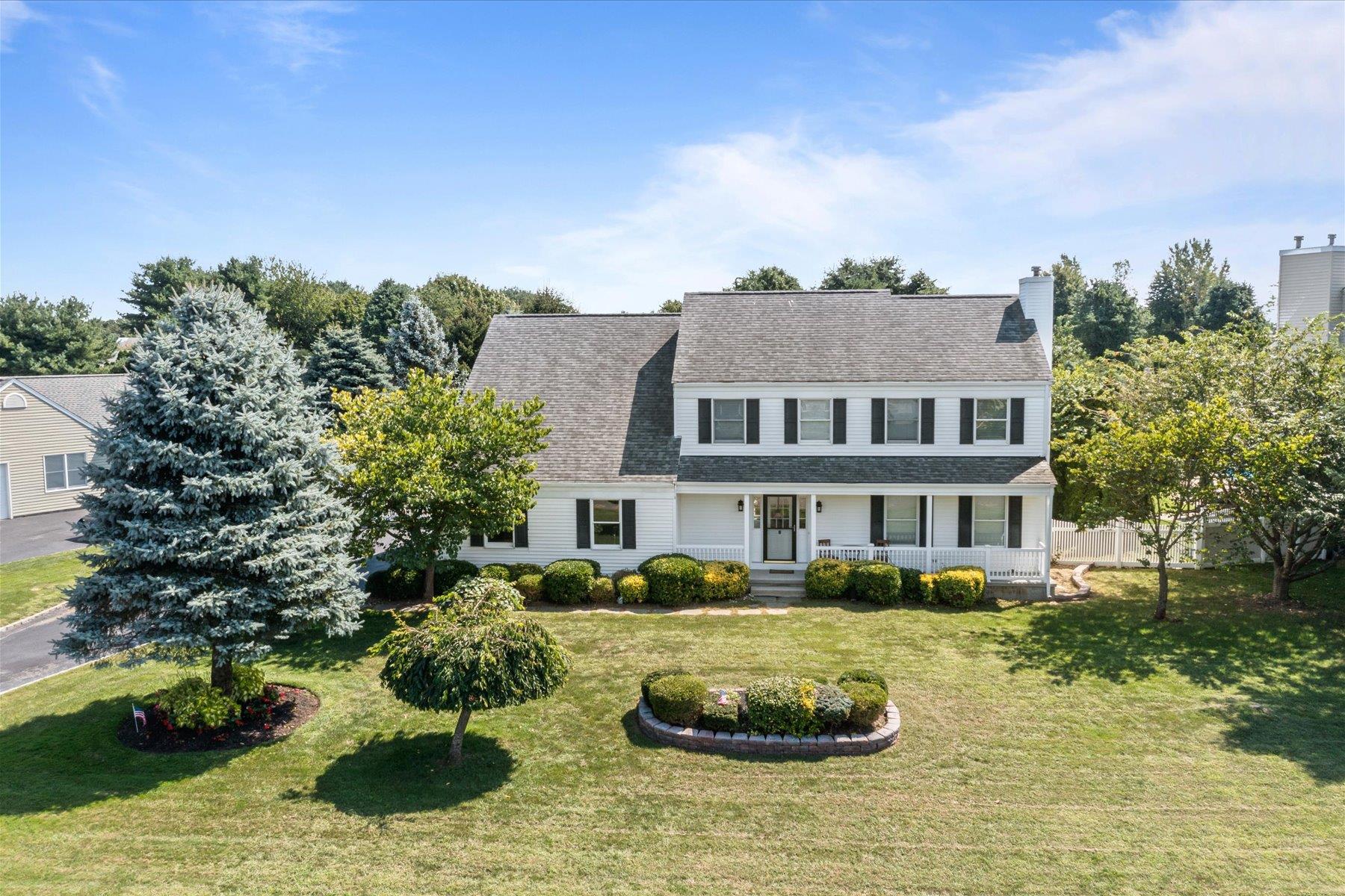 Colonial-style house featuring a front lawn and a porch