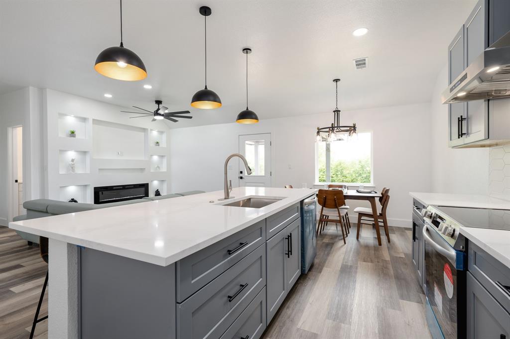 a kitchen with a sink a stove and a wooden floor