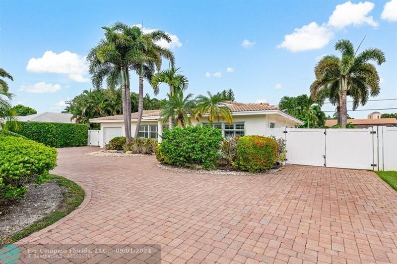 a palm tree sitting in front of a house with potted plants