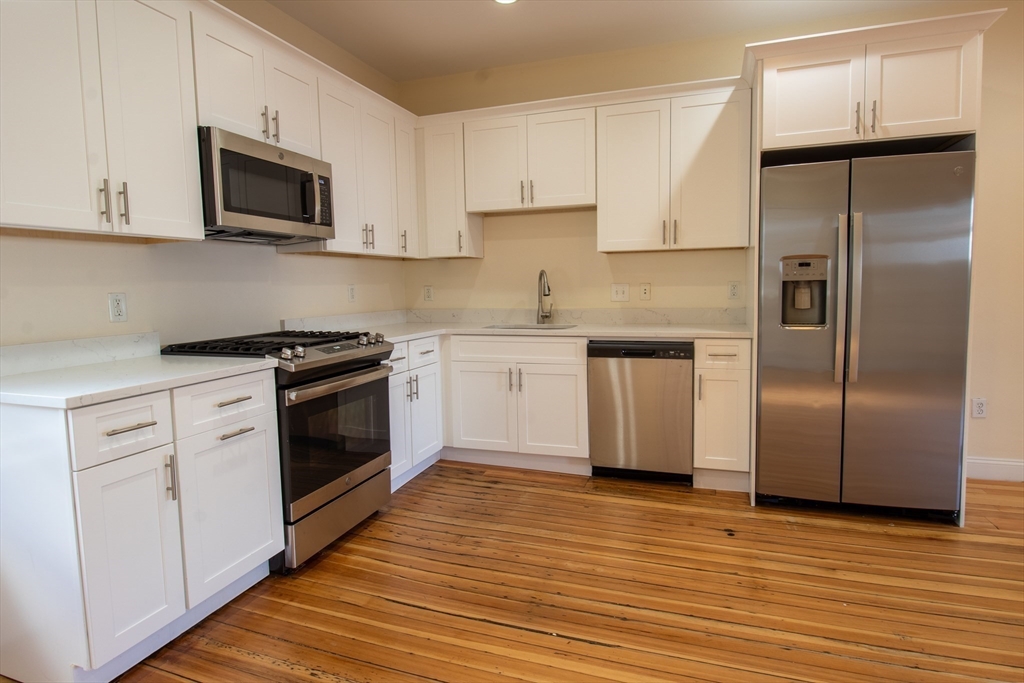 a kitchen with cabinets stainless steel appliances and wooden floor