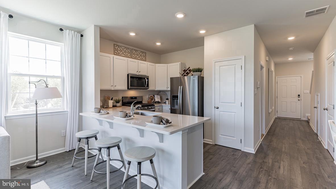 a kitchen with refrigerator a sink and chairs