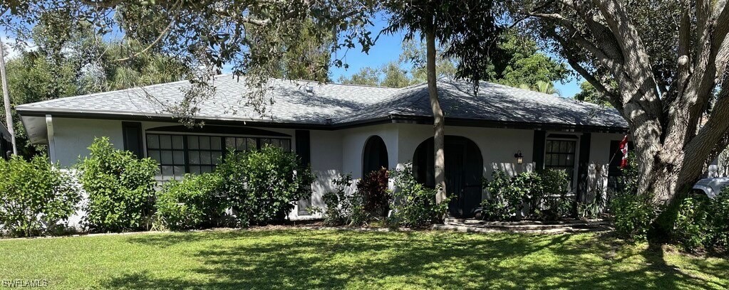 a view of a house with potted plants and a large tree