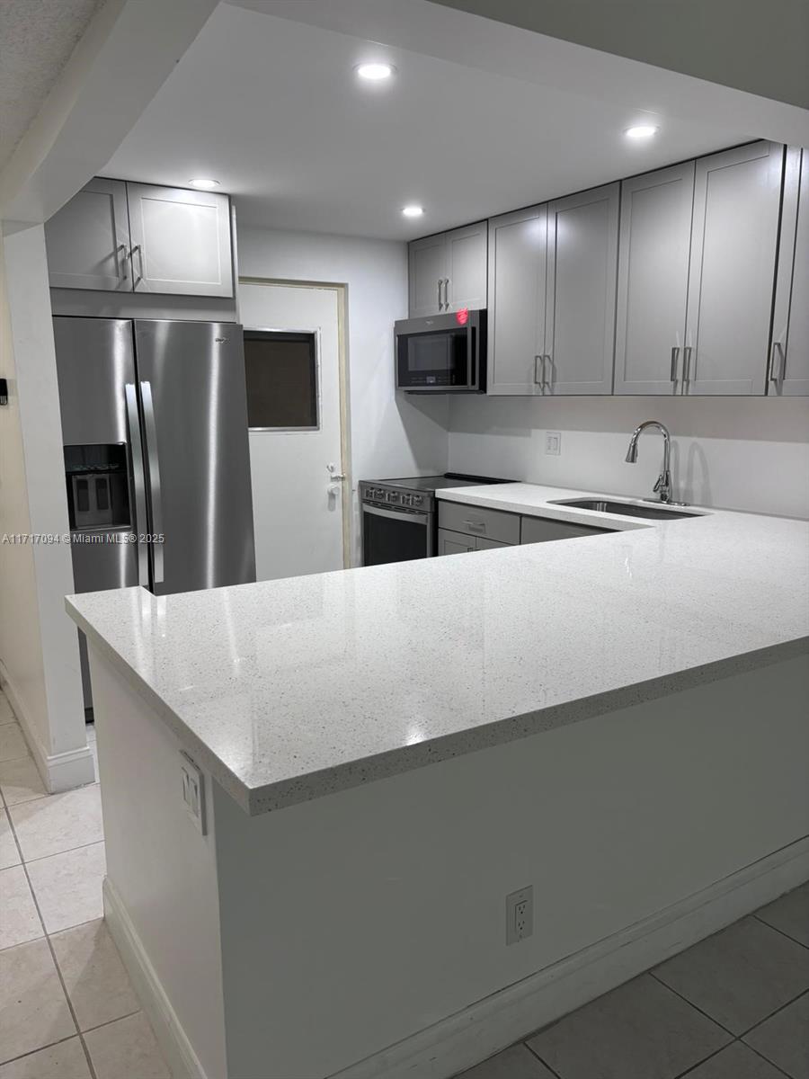 a large kitchen with granite countertop a large counter top stainless steel appliances and cabinets