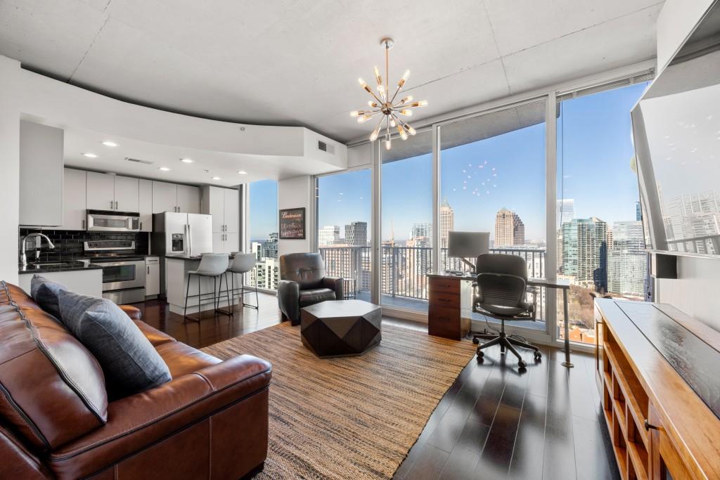 a living room with furniture kitchen view and a chandelier