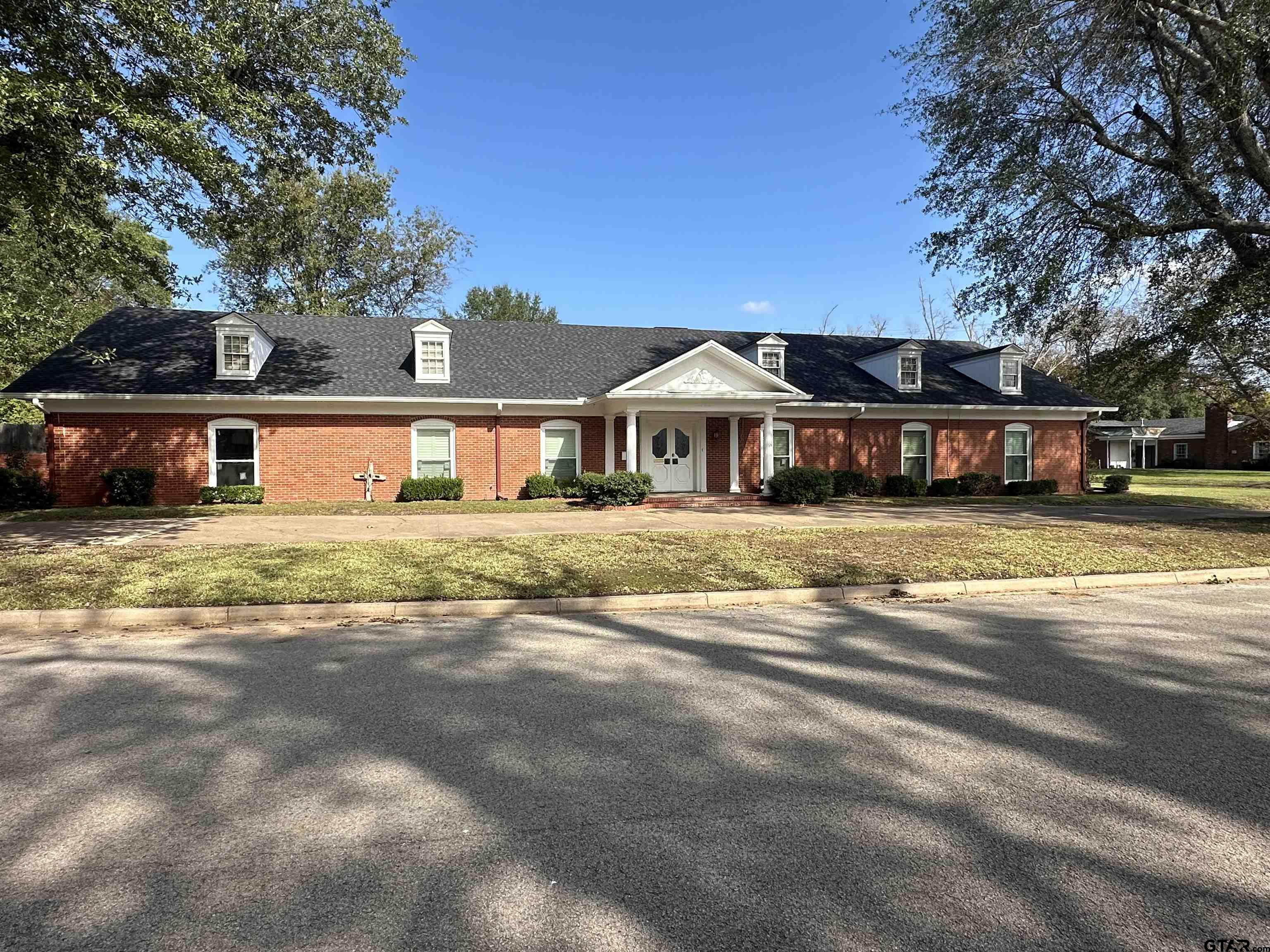 a view of a house with a big yard and large trees