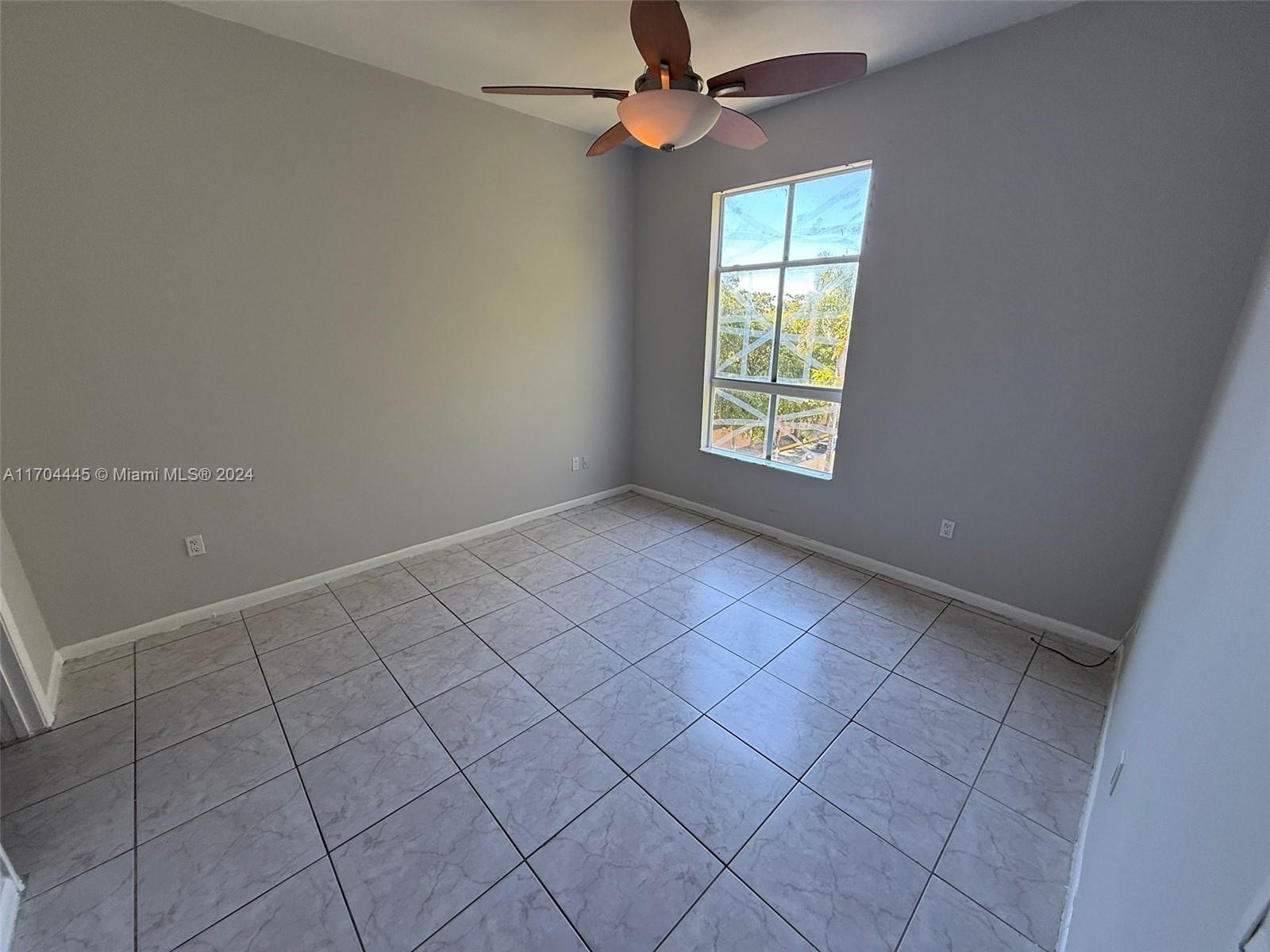 an empty room with windows and fan