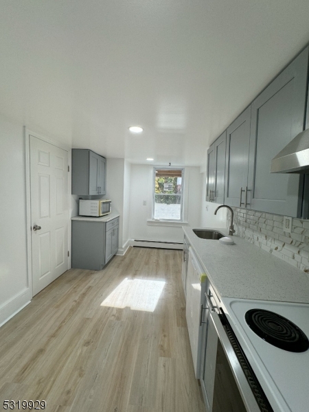 a large kitchen with a stove a sink dishwasher and a refrigerator with wooden floor