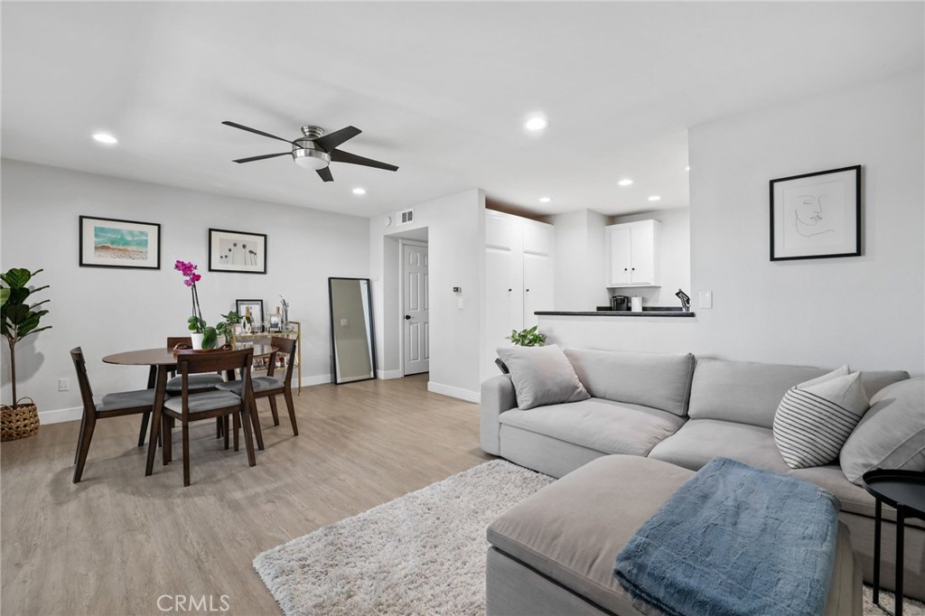 a living room with furniture and a dining table with wooden floor