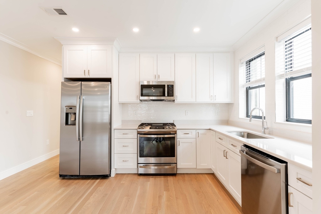 a kitchen with a sink a microwave a refrigerator and cabinets