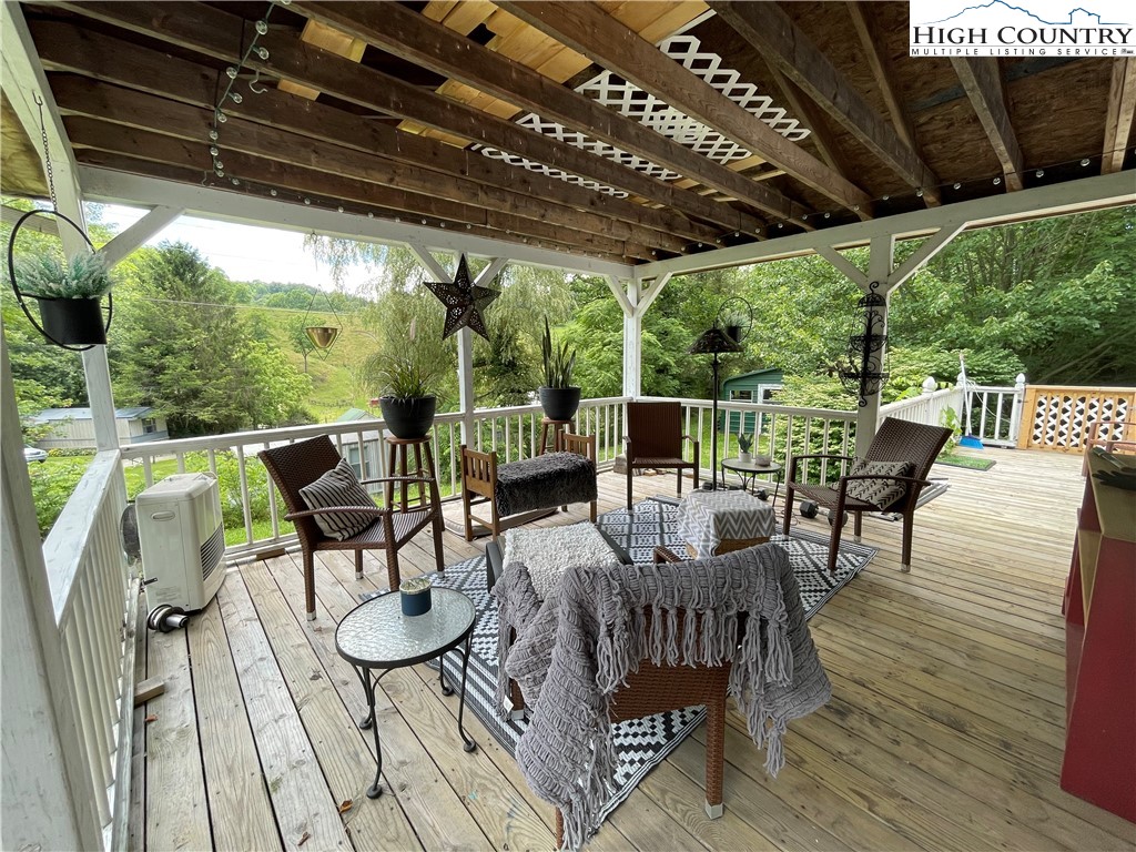 a view of a patio with table and chairs potted plants with wooden floor and floor to ceiling window