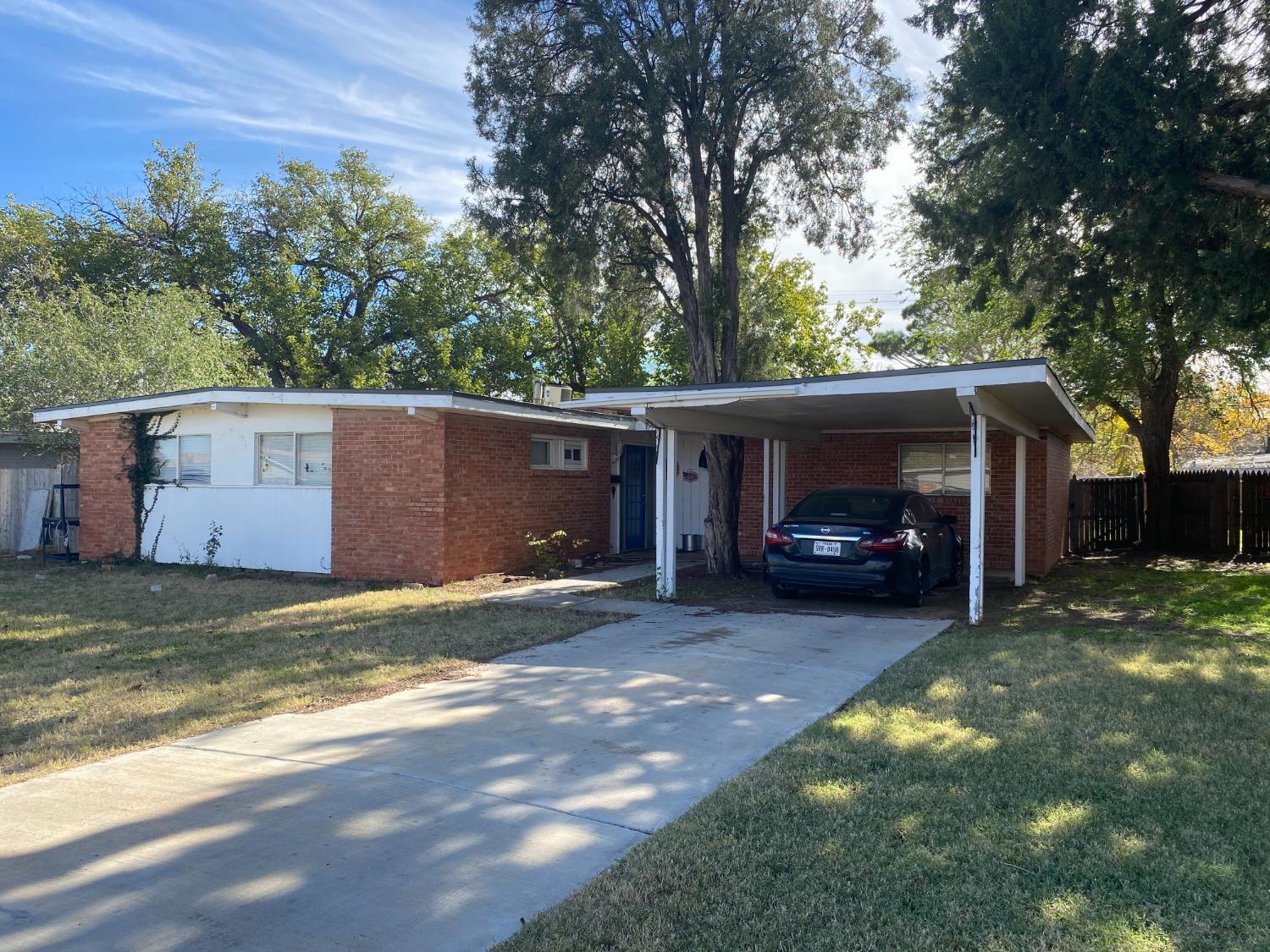 a view of a house with a large tree and a car parked in front of it