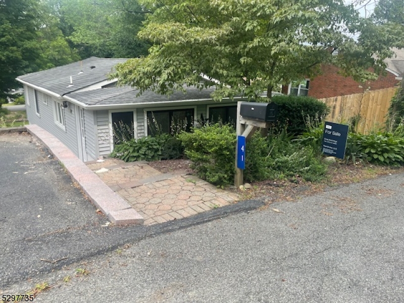 a view of a house with potted plants and large trees