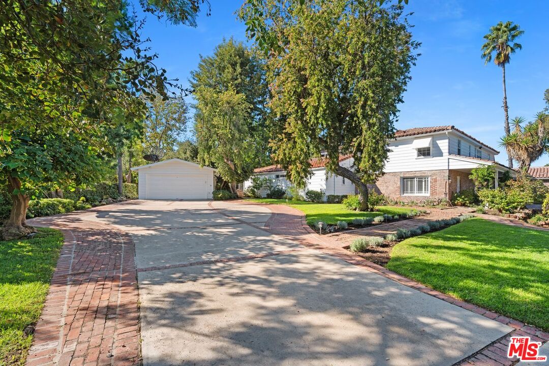 a view of a house with a yard and large trees