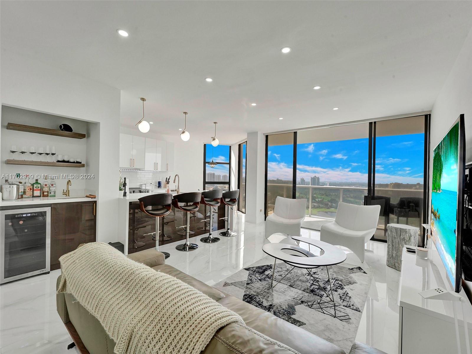 a living room with furniture kitchen view and large windows