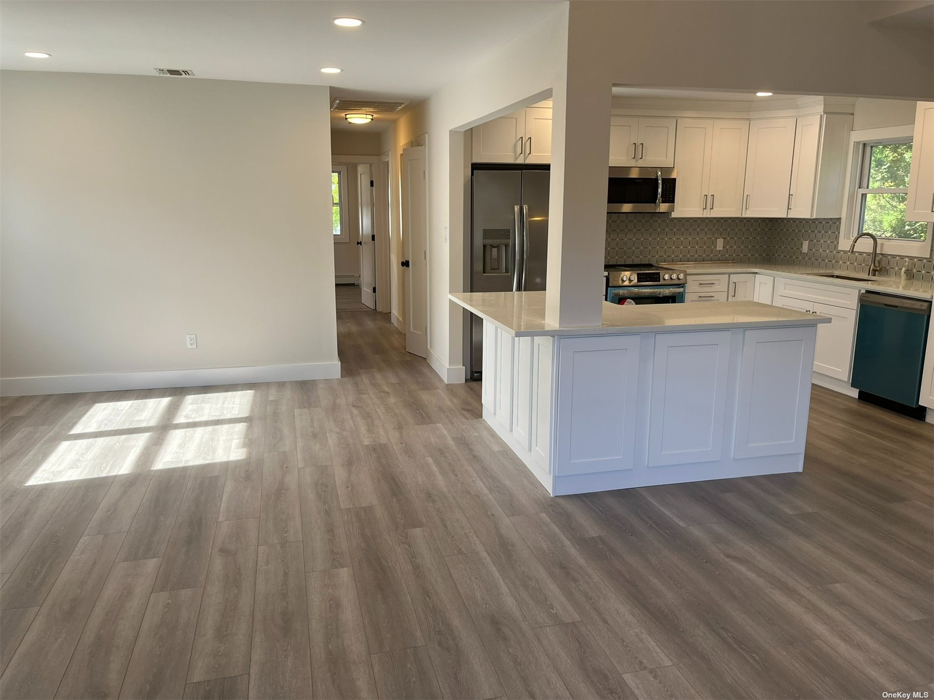 a large kitchen with stainless steel appliances wooden floors and large window