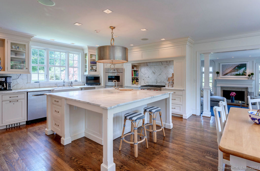 a kitchen with stainless steel appliances granite countertop a kitchen island hardwood floor sink stove dining table and chairs