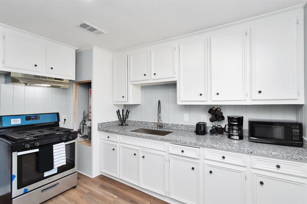 a kitchen with granite countertop white cabinets and black appliances